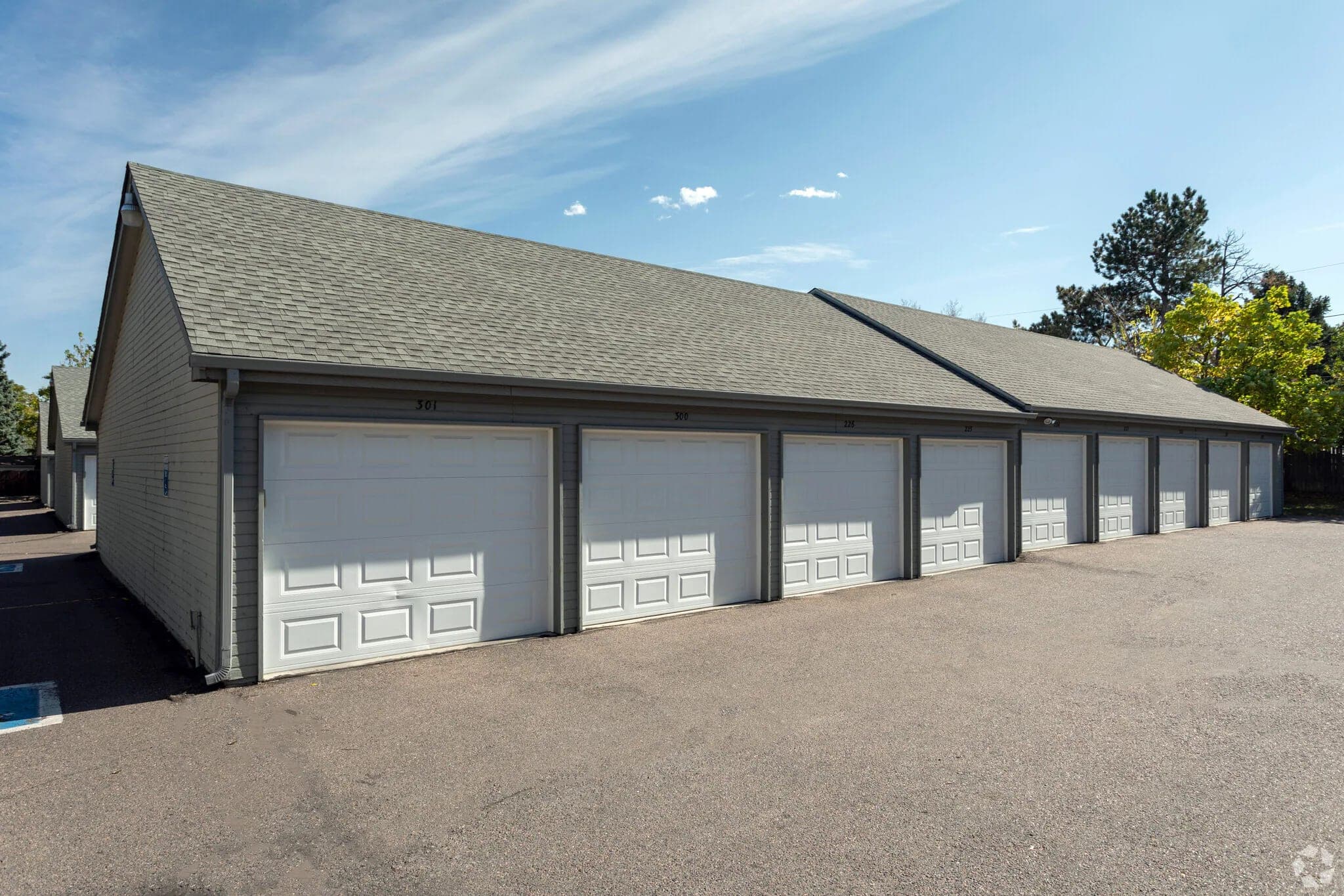 A row of nine private garages with individual numbered doors, across the parking area from the apartment buildings.